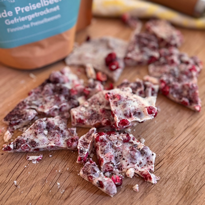 Frostige weiße Schokoladenleckereien mit roten Preiselbeeren auf einer Holzoberfläche.