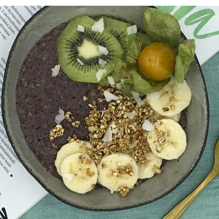 Johannisbeer-Haferbrei in einer Schüssel mit Früchten und Granola auf einem grünen Tischcloth.