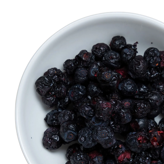 Eine weiße Schüssel, gefüllt mit gefriergetrockneten wilden finnischen Heidelbeeren.