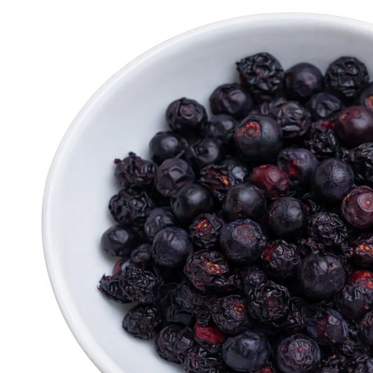 Weisse Schüssel, gefüllt mit tiefpurpurfarbenen, gefriergetrockneten Schwarze Johannisbeeren.