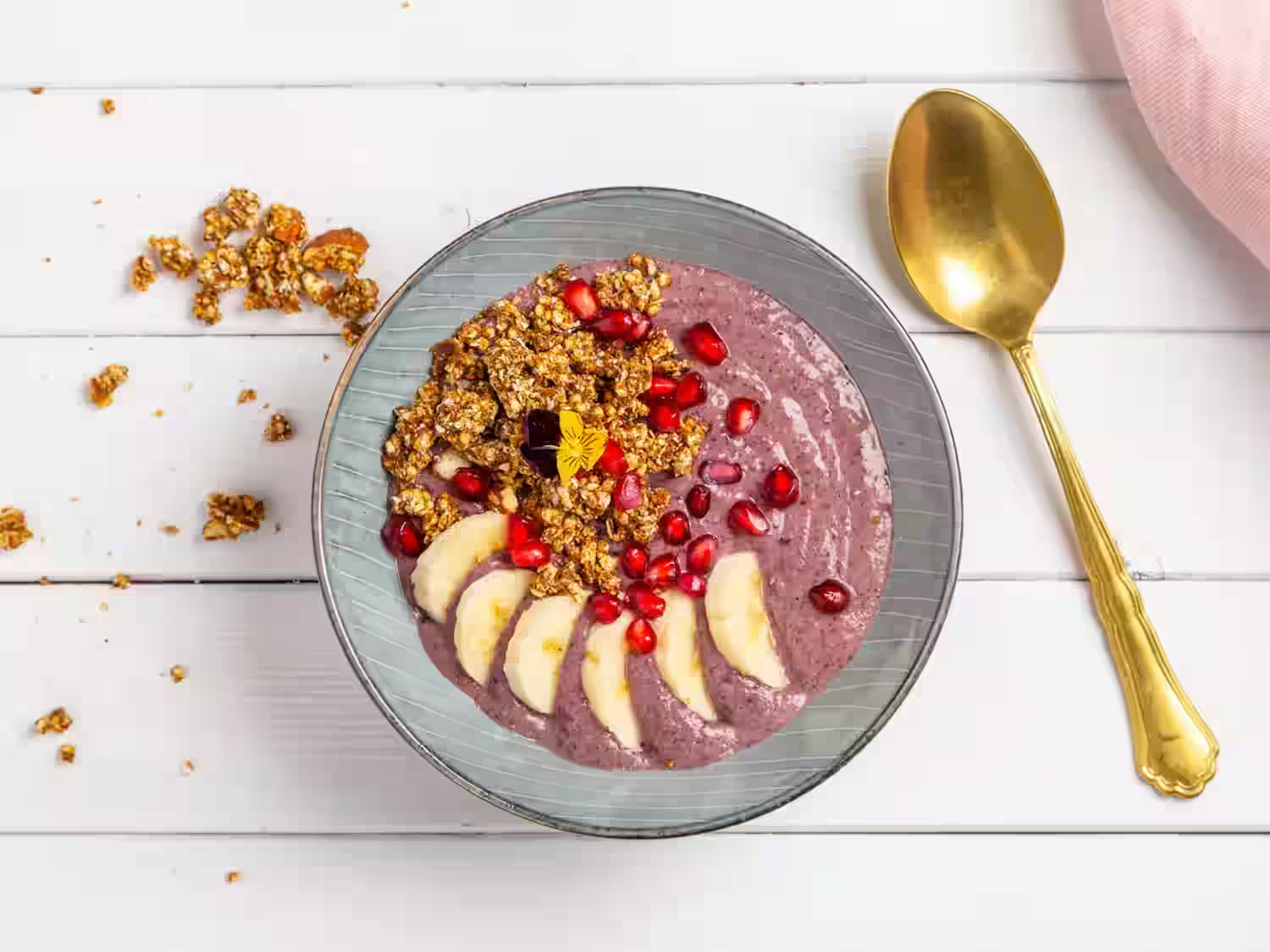 Smoothie-Bowl mit Granola, Bananen und Granatapfelkernen.