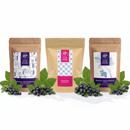 Drei Pure Nordic Beutel mit schwarzen Johannisbeeren und Haferflocken, umgeben von schwarzen Beeren.