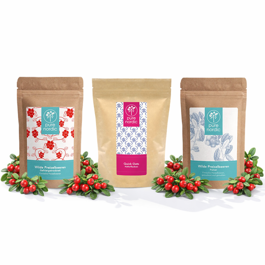 Drei Pure Nordic Beutel mit Preiselbeeren und Haferflocken umgeben von roten Beeren.